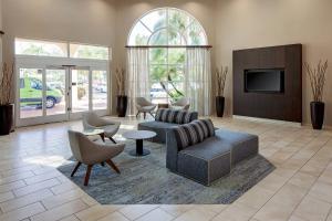 uma sala de estar com um sofá e cadeiras e uma televisão em Courtyard by Marriott Fort Lauderdale North/Cypress Creek em Fort Lauderdale