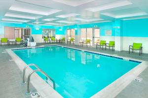 - une piscine avec des tables et des chaises dans une chambre d'hôtel dans l'établissement SpringHill Suites Fairfax Fair Oaks, à Fairfax