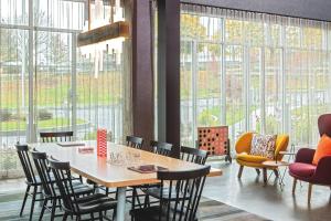 a dining room with a table and chairs and windows at Aloft Framingham in Framingham