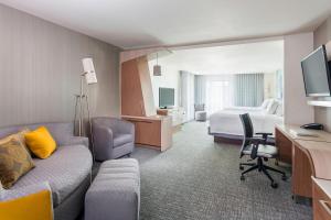 a hotel room with a couch and a bed at Courtyard by Marriott Stafford Quantico in Triangle
