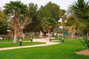 a park with palm trees and a path at Le Meridien Al Khobar in Al Khobar
