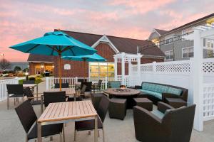 patio ze stołami i krzesłami oraz niebieskim parasolem w obiekcie Residence Inn by Marriott Peoria w mieście Peoria