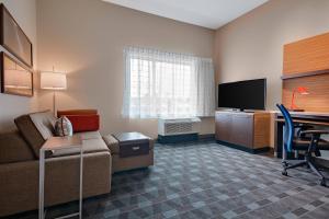 Habitación de hotel con sofá, escritorio y TV en TownePlace Suites by Marriott Detroit Allen Park, en Allen Park
