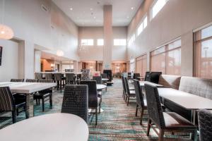 a dining room with tables and chairs and windows at Residence Inn by Marriott Charlotte Airport in Charlotte