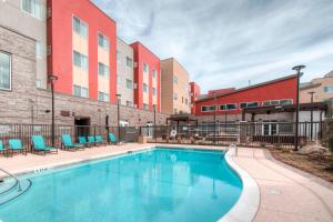 Residence Inn by Marriott Charlotte Airport في تشارلوت: مسبح وكراسي ومبنى