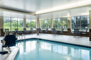 a swimming pool with chairs and tables in a building at Fairfield Inn & Suites Minneapolis North in Brooklyn Center