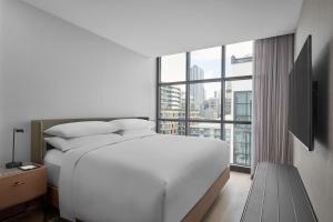 a bedroom with a white bed and a large window at Courtyard by Marriott Melbourne Flagstaff Gardens in Melbourne