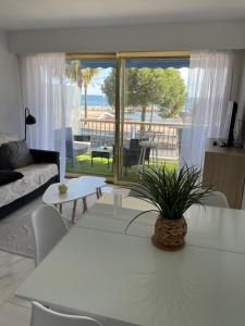 una sala de estar con una mesa blanca con una planta. en Front de mer,plage, piscine, parking, en Cagnes-sur-Mer