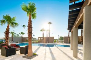 - une piscine avec des palmiers et des chaises longues dans l'établissement Courtyard by Marriott Hermosillo, à Hermosillo