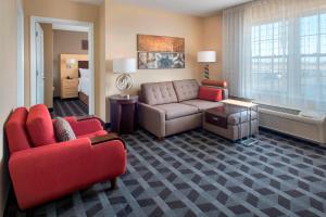 a living room with a couch and a room with a bed at TownePlace Suites Republic Airport Long Island Farmingdale in Farmingdale