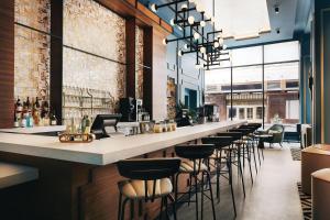 a bar with a row of bar stools at Kinley Cincinnati Downtown, a Tribute Portfolio Hotel in Cincinnati