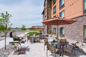 un patio con mesas, sillas y una sombrilla en TownePlace Suites by Marriott Billings en Billings