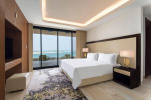 a bedroom with a large white bed and a large window at Agora, Doha, Autograph Collection in Doha