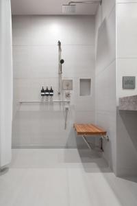 a white bathroom with a shower and a bench at TETRA Hotel, Autograph Collection in Sunnyvale