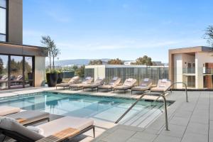 a swimming pool with lounge chairs on a building at TETRA Hotel, Autograph Collection in Sunnyvale