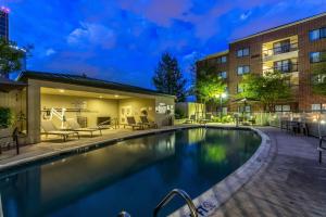 einen Swimmingpool mit Stühlen und einem Gebäude in der Unterkunft Courtyard Dallas DFW Airport South/Irving in Irving