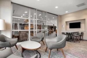 a lobby with chairs and a table and a tv at Courtyard by Marriott Jonesboro in Jonesboro