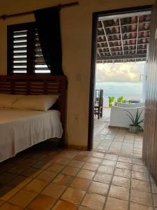 a bedroom with a bed and a balcony with a tub at Pousada Casa Feliz Maxaranguape in Maxaranguape