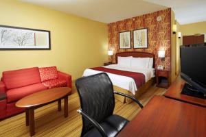 a hotel room with a bed and a red couch at Courtyard Altoona in Altoona