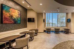 a waiting room with tables and chairs and a painting on the wall at SpringHill Suites by Marriott Dallas Rockwall in Rockwall