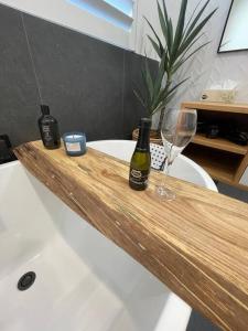 a bath tub with two bottles of wine and a glass at Yellow Door Villa in Barwon Heads
