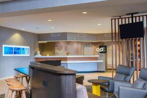 SpringHill Suites Grand Rapids North في غراند رابيدز: غرفة معيشة مع مطبخ مع طاولة وكراسي