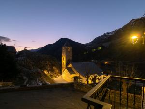a building with a clock tower with mountains in the background at Apartamentos Ca de Marti in Bohí