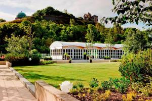 a building in a garden with a hill in the background at The Glasshouse, Autograph Collection in Edinburgh