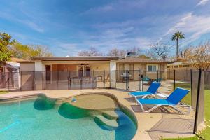 a swimming pool with two chairs and a house at Piestewa Getaway in Phoenix