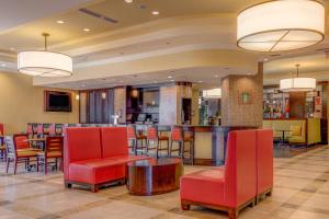 a hotel lobby with red chairs and a bar at Macon Marriott City Center in Macon