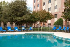 basen z niebieskimi krzesłami i budynek w obiekcie Courtyard Dallas Addison Quorum Drive w mieście Addison