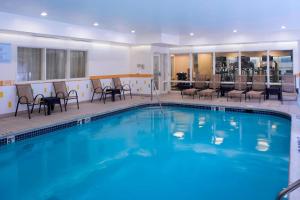 einen großen Pool mit Stühlen und einem Tisch in der Unterkunft Fairfield Inn & Suites Detroit Farmington Hills in Farmington Hills