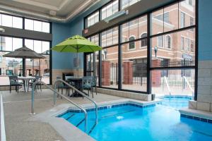 a swimming pool with an umbrella in a building at Courtyard by Marriott Holland Downtown in Holland