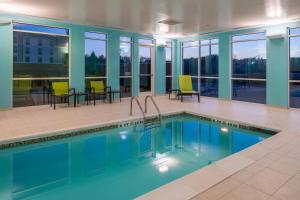 a pool in a building with chairs and a table at SpringHill Suites by Marriott Greensboro Airport in Friendship