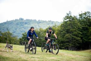 dos personas montando bicicletas en un campo con un perro en GITE DES 3 JONQUILLES, en Saint-Maurice-sur-Moselle