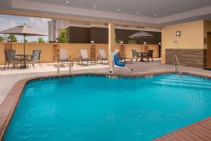 Fairfield Inn & Suites by Marriott New Orleans Metairie في ميتايري: مسبح كبير مع كراسي وطاولات في الفندق
