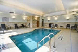 - une piscine dans un hôtel avec des chaises et des tables dans l'établissement Fairfield Inn & Suites by Marriott Milwaukee North, à Glendale