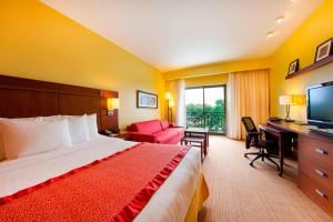 a hotel room with a bed and a desk and a television at Courtyard by Marriott Paramaribo in Paramaribo