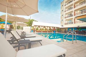 uma piscina do hotel com espreguiçadeiras e um guarda-sol em Courtyard by Marriott Paramaribo em Paramaribo