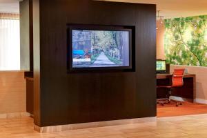 a flat screen tv on a wall with a desk at Courtyard by Marriott Lexington North in Lexington