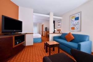 ein Hotelzimmer mit einem blauen Sofa und einem TV in der Unterkunft Fairfield Inn and Suites by Marriott Asheboro in Asheboro