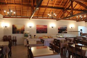 a dining room with white tables and chairs and wooden ceilings at Hotel San Lucas in Gramado