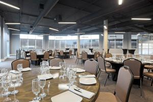 a large room with tables and chairs with glasses on them at Courtyard by Marriott Montreal West Island/Baie D’Urfe in Baie-dʼUrfé