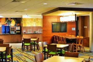 Fairfield Inn & Suites by Marriott Omaha Northwest في أوماها: غرفة طعام بها طاولات وكراسي وتلفزيون بشاشة مسطحة