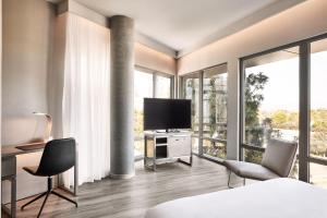 sypialnia z łóżkiem, 2 krzesłami i telewizorem w obiekcie AC Hotel by Marriott Sunnyvale Moffett Park w mieście Sunnyvale