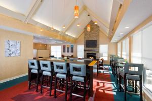 a restaurant with a bar with stools and a fireplace at Residence Inn Youngstown Boardman/Poland in Poland