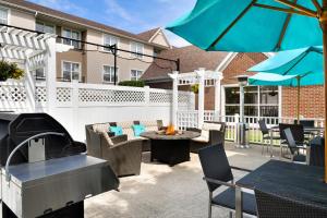 une terrasse avec une table, des chaises et un parasol dans l'établissement Residence Inn Youngstown Boardman/Poland, à Poland