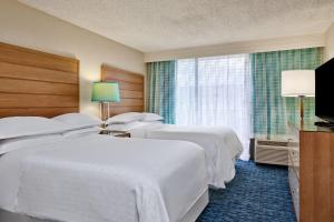 a hotel room with four beds and a window at Sheraton Orlando Lake Buena Vista Resort in Orlando