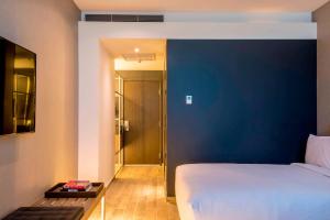 a bedroom with a bed and a blue wall at AC Hotel Queretaro Antea in Querétaro