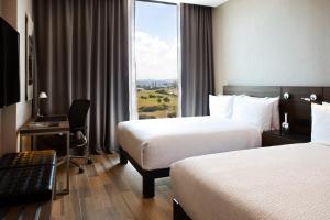 a hotel room with two beds and a desk and a window at AC Hotel Queretaro Antea in Querétaro